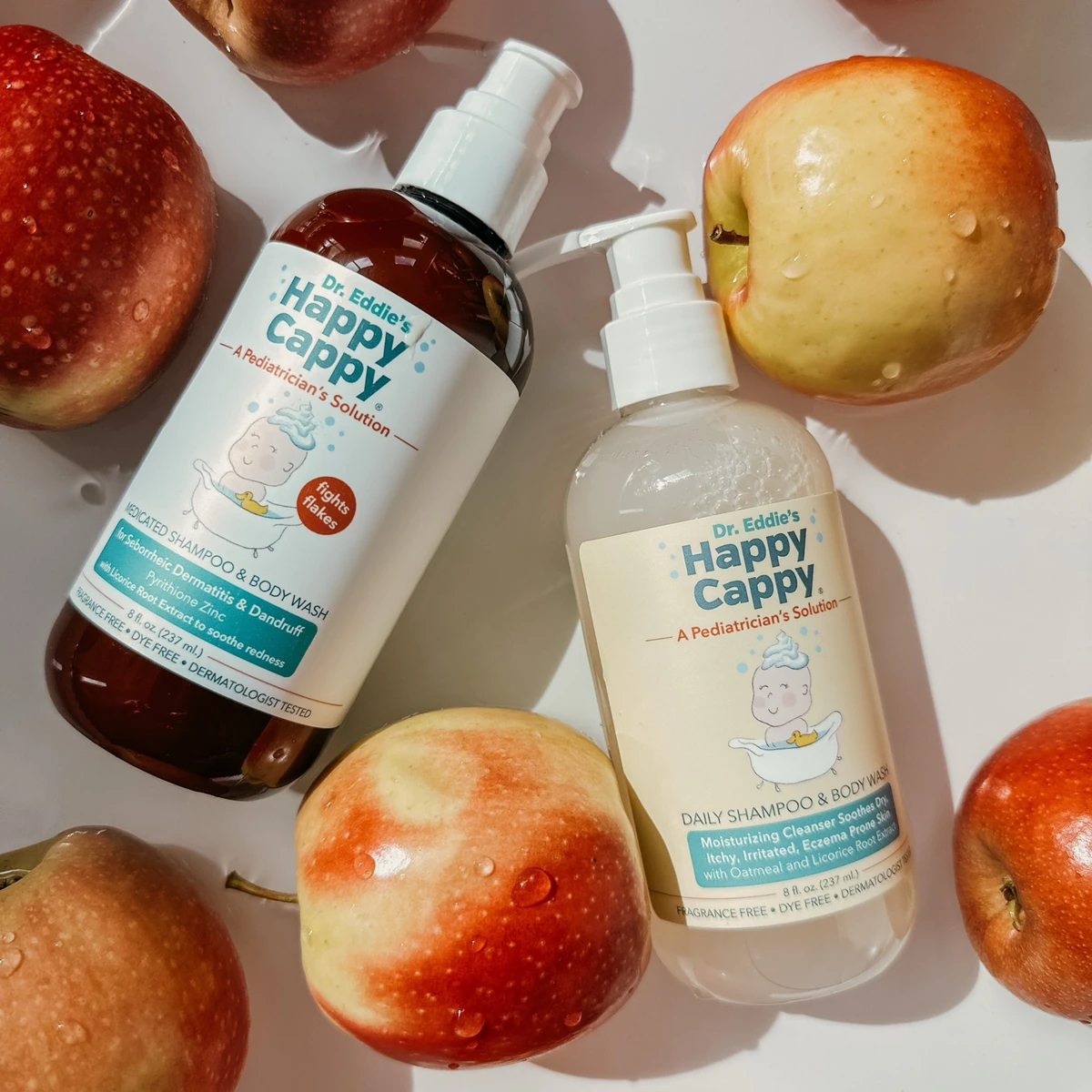 Happy Cappy Medicated and Daily Shampoo & Body Wash bottles arranged with apples.