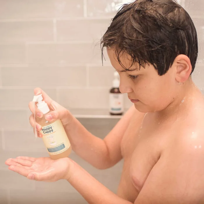 Boy in the shower dispensing Happy Cappy daily shampoo and body wash into his hand
