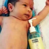 Newborn lying on a changing pad next to the Happy Cappy daily wash bottle