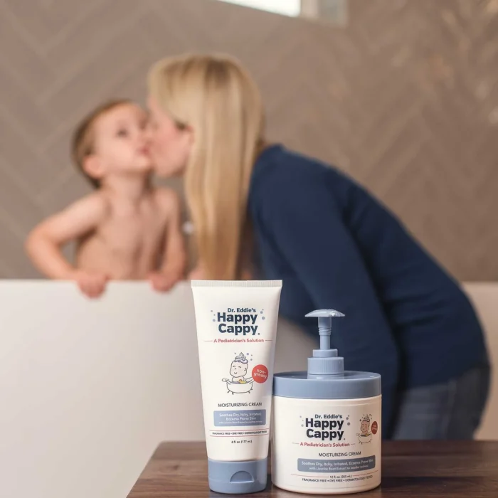 Happy Cappy moisturizing cream tube and jar with a mother kissing her child behind
