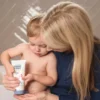 Toddler squeezing Happy Cappy moisturizing cream from the tube with a parent