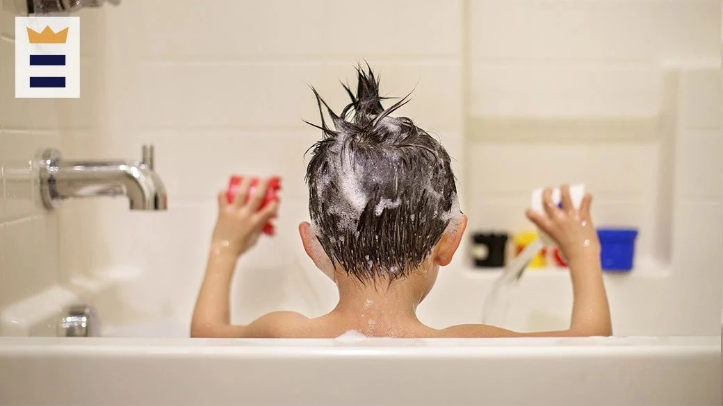 Niño visto de espaldas con espuma de champú en el cabello durante el baño, en la imagen original del archivo de prensa.